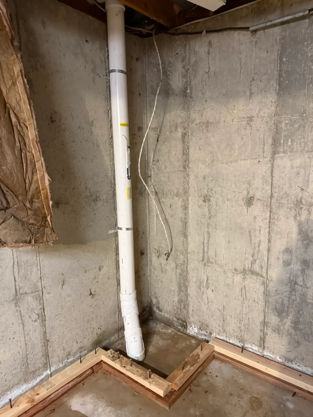 Radon mitigation pipe running up through a basement corner in Lafayette, CO