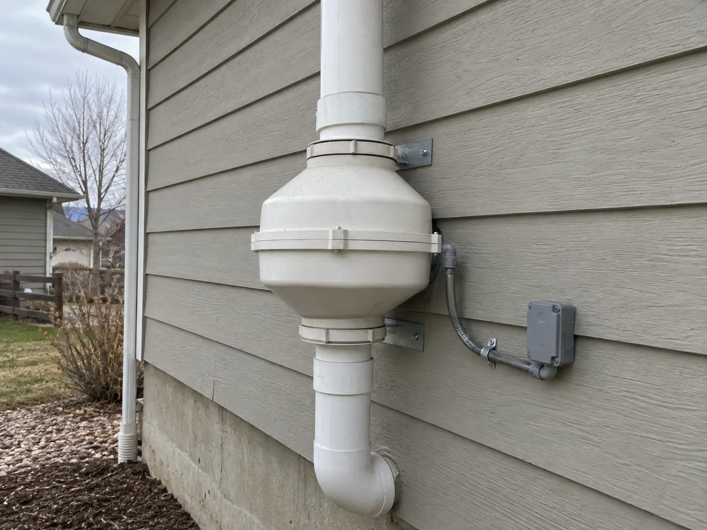 Radon mitigation fan mounted on the exterior wall of a Lafayette, CO home